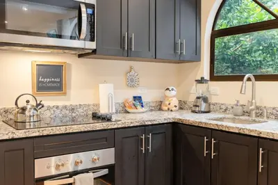a kitchen with black cabinets and a sink at Suite 3 Jaguar - Beach & Pool 2 BR Condo in Brasilito