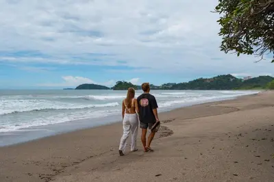 a man and a woman walking on the beach at Suite 3 Jaguar - Beach & Pool 2 BR Condo in Brasilito