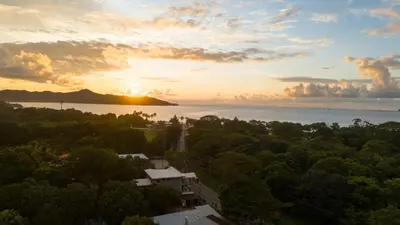 a sunset over the ocean with a house and trees at Suite 4 Sloth - Pool&Beach 3 BR Condo in Brasilito