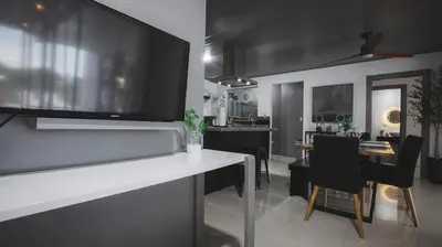 a kitchen and dining room with a large tv on the wall at Villa Diriá La Fortuna - Downtown Home in Fortuna
