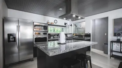 a kitchen with a stainless steel refrigerator and a counter at Villa Diriá La Fortuna - Downtown Home in Fortuna