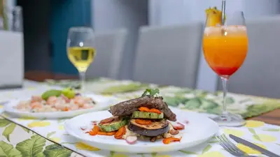 a table with two plates of food and two glasses of wine at Villa Diriá La Fortuna - Downtown Home in Fortuna