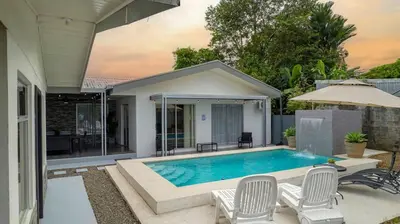 a swimming pool with chairs and a house at Villa Diriá La Fortuna - Downtown Home in Fortuna