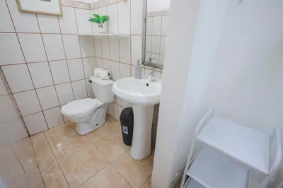 a white bathroom with a toilet and a sink at Villa Diriá La Fortuna - Downtown Home in Fortuna