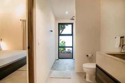 a bathroom with a toilet and a bed and a window at Rincon Escondido in Nosara