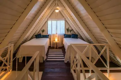 a attic room with two beds and a window at Casa Jose in Nosara