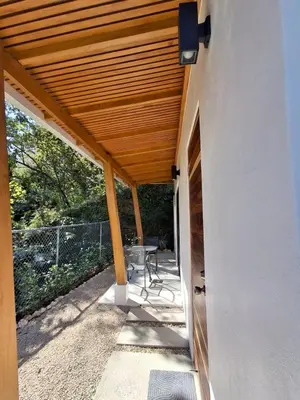 a patio with a wooden roof with a chair under it at Casa Manzu in Nosara