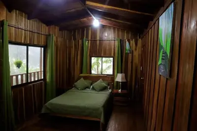 a bedroom with a green bed and a window at VA Logde in Monteverde Costa Rica