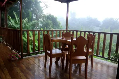 a wooden deck with a table and chairs on a balcony at VA Logde in Monteverde Costa Rica