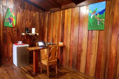 a room with a wooden wall with a desk and a refrigerator at VA Logde in Monteverde Costa Rica
