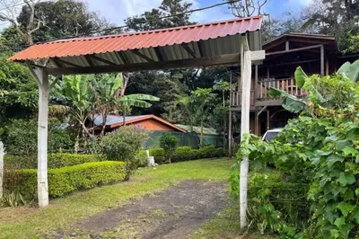 a wooden pergola in a yard with a house at VA Logde in Monteverde Costa Rica
