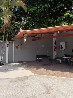 a building with awning and a table and chairs at Thompson House in Orotina