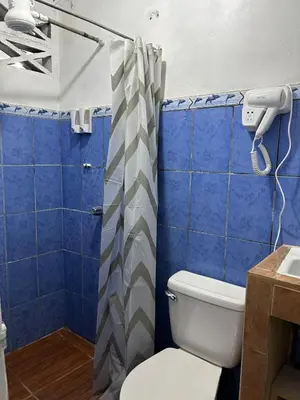a bathroom with a toilet and blue tiles at Perezoso View Apartment in Guápiles