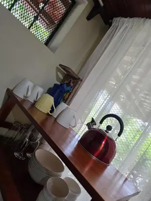 a kitchen counter with a window with a tea kettle on it at Cabinas MaWa Tropical 5 minutos a playa in Uvita