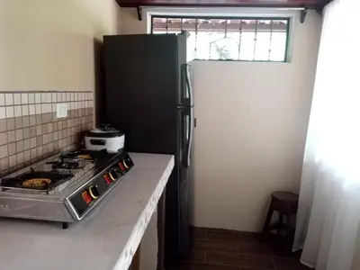a kitchen with a stove and a refrigerator at Cabinas MaWa Tropical 5 minutos a playa in Uvita