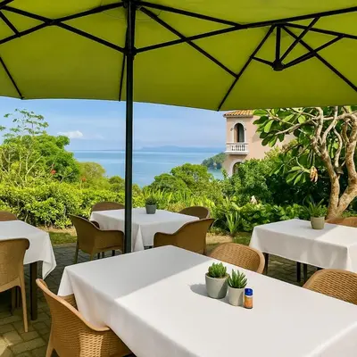 a group of tables and chairs under a green umbrella at Mi Zaru Sea View Hotel Free Park Tour & Breakfast in Manuel Antonio