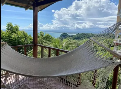 a hammock on a balcony with a view of the ocean at Mi Zaru Sea View Hotel Free Park Tour & Breakfast in Manuel Antonio