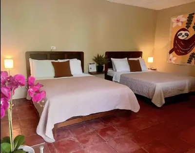 two beds in a hotel room with pink flowers at Mi Zaru Sea View Hotel Free Park Tour & Breakfast in Manuel Antonio