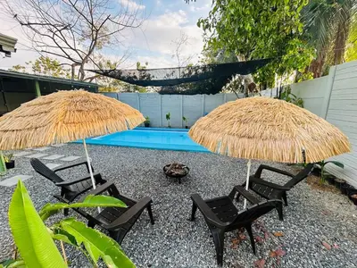 two straw umbrellas and two chairs and a pool at House with a private swimming pool in Chontales