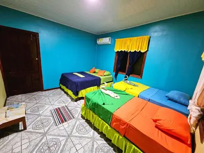 two beds in a room with blue walls at Cabinas Miss Miriam 2 in Tortuguero