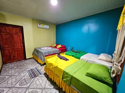 two beds in a room with blue and green at Cabinas Miss Miriam 2 in Tortuguero