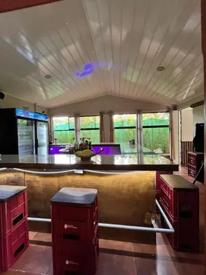 a room with a bar with red cabinets and windows at Casa Club Bluaska in Sarapiquí