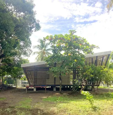 a bench and a tree in front of a building at Awarded No Footprint House on Matapalo Beach in Savegre