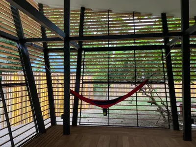 a hammock is hanging in a room with large windows at Awarded No Footprint House on Matapalo Beach in Savegre