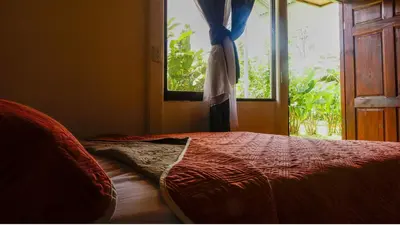 a bed in a room with a window and a bedspread at Rio Celeste Cabinas Vista Tenorio in El pilon