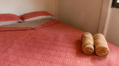 a bed with a red comforter and two pillows at Rio Celeste Cabinas Vista Tenorio in El pilon