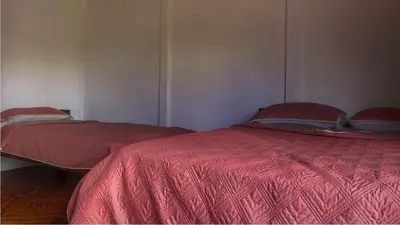 two beds in a room with red comforter at Rio Celeste Cabinas Vista Tenorio in El pilon