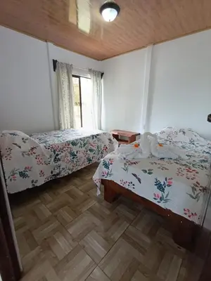 a bedroom with two beds and a wooden floor at Ibis House, Bijagua in Upala
