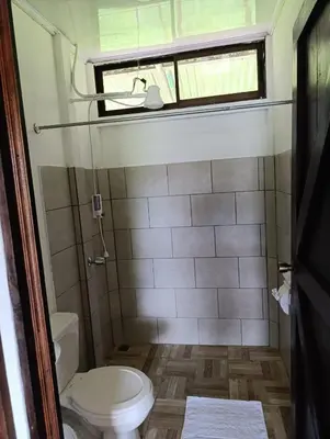 a small bathroom with a toilet and a window at Ibis House, Bijagua in Upala