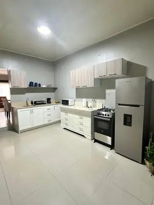 a large kitchen with white cabinets and a refrigerator at Venus Home in Guápiles