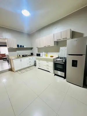 a large kitchen with white cabinets and a refrigerator at Venus Home in Guápiles