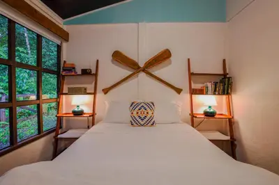a bedroom with a large bed and two windows at Coco Cabana in the Jungle in Sarapiquí