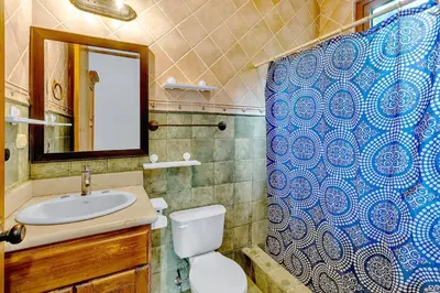 a bathroom with a toilet and a sink and a mirror at Palacio Tropical- Secluded & Private Beach in Puntarenas