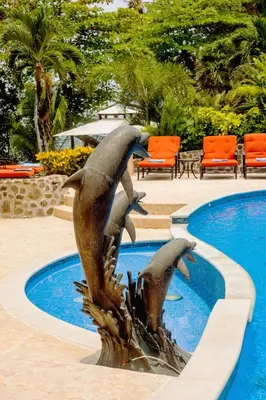 a dolphin fountain in front of a swimming pool at Palacio Tropical- Secluded & Private Beach in Puntarenas