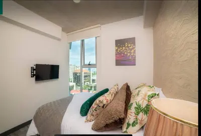 a bedroom with a bed with pillows and a window at Dreamliner at 11s, City Views and Wonderland Vibes! in Hatillo