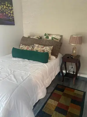 a bedroom with a bed and a table with a lamp at Dreamliner at 11s, City Views and Wonderland Vibes! in Hatillo