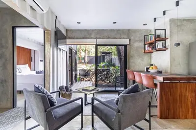 a kitchen and living room with a bar and chairs at Z102 Studios, 4 Industrial Beach Condos w Pool! in Playa Flamingo