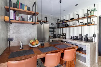 a kitchen with a wooden table and orange chairs at Z102 Studios, 4 Industrial Beach Condos w Pool! in Playa Flamingo