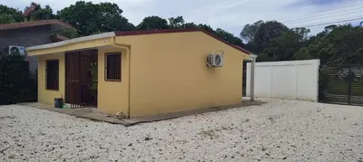 a small yellow house sitting on top of gravel at Capi-Capi Retreat in Paquera