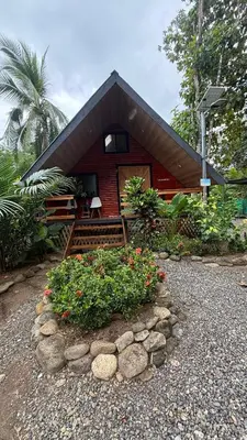 a small red house with some flowers in front of it at Cabaña Vacal Wifi, beach front #2 in Uvita