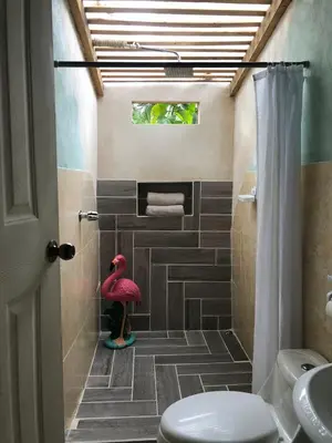 a bathroom with a pink flamingo in the shower at Cabaña Vacal Wifi, beach front #2 in Uvita