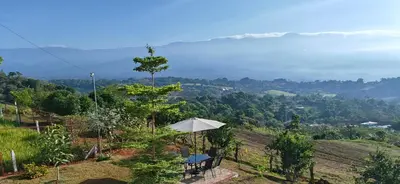 a table and an umbrella on top of a hill at Home in Perez Zeledon with Chirripó Views in Angostura