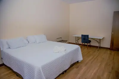 a bedroom with a bed with a white blanket and a table at Home in Perez Zeledon with Chirripó Views in Angostura