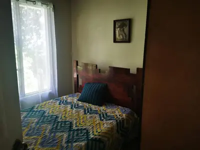 a bedroom with a bed with a comforter and a window at Casa Tucan in Aguas Zarcas