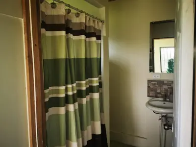 a bathroom with a green and white shower curtain at Casa Tucan in Aguas Zarcas