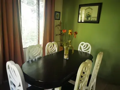 a dining room with a black table and white chairs at Casa Tucan in Aguas Zarcas